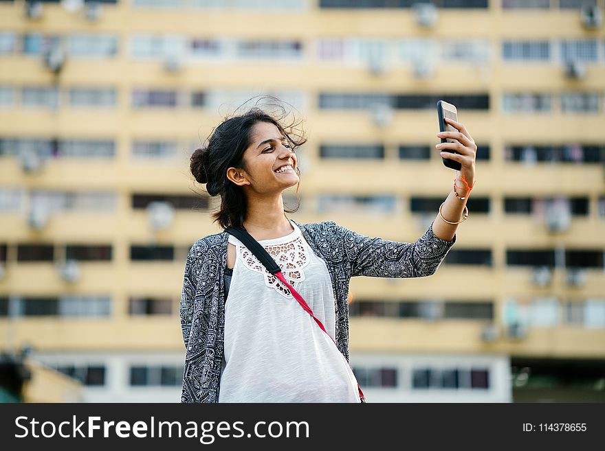 Smiling Woman Holding Black Smartphone