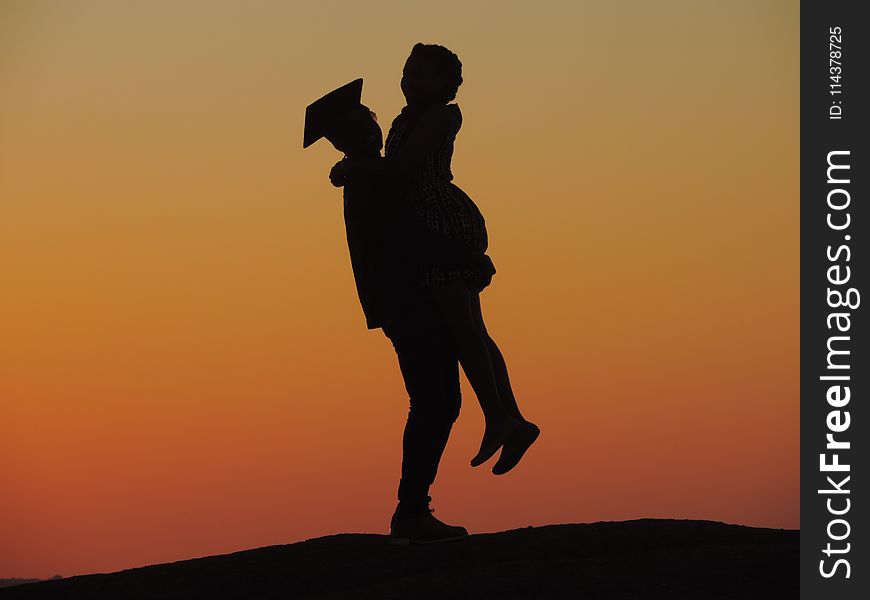 Silhouette Photo Of Man Carrying Woman Under Orange Sky