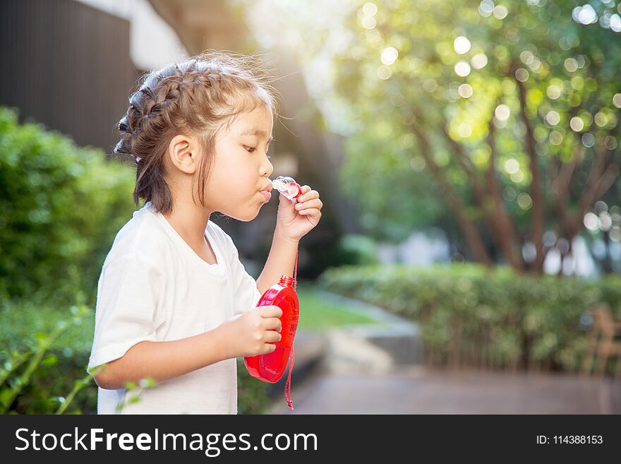 Asian kid focus on playing bubble on park.