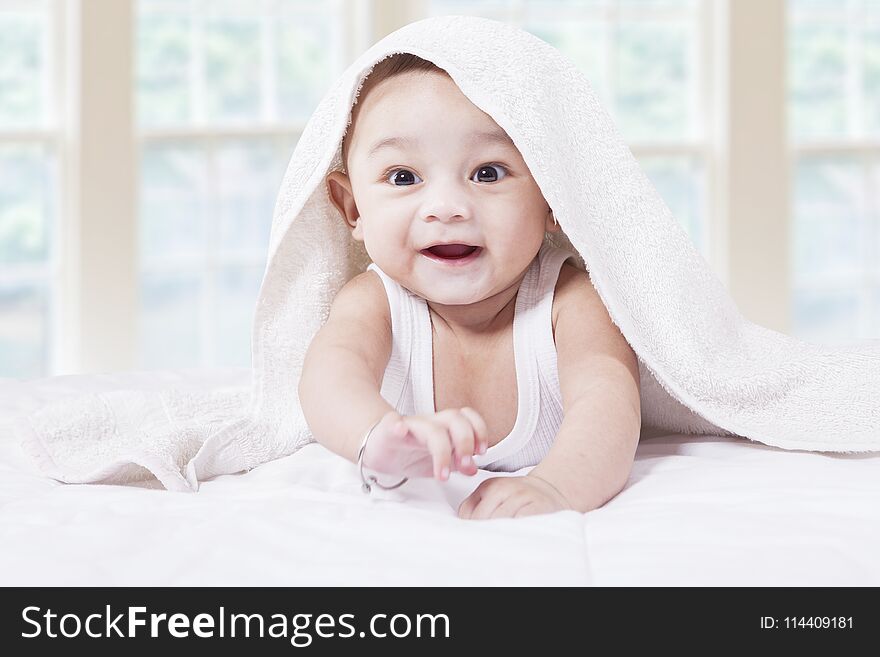 Closeup of joyful male toddler crawling on the bedroom under a towel. Closeup of joyful male toddler crawling on the bedroom under a towel