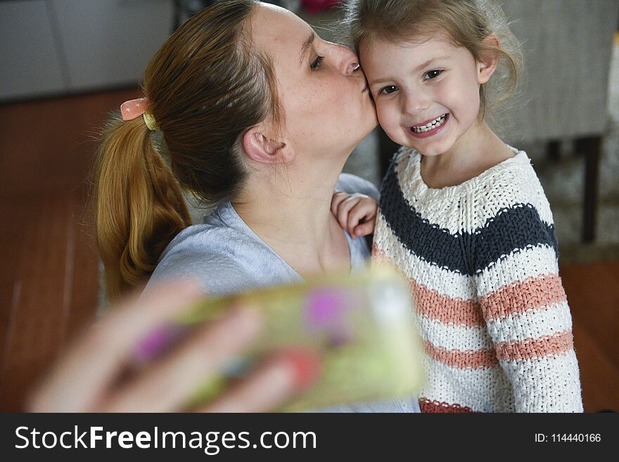 Young mother makes selfie photo with her little daugther at home. Young mother makes selfie photo with her little daugther at home