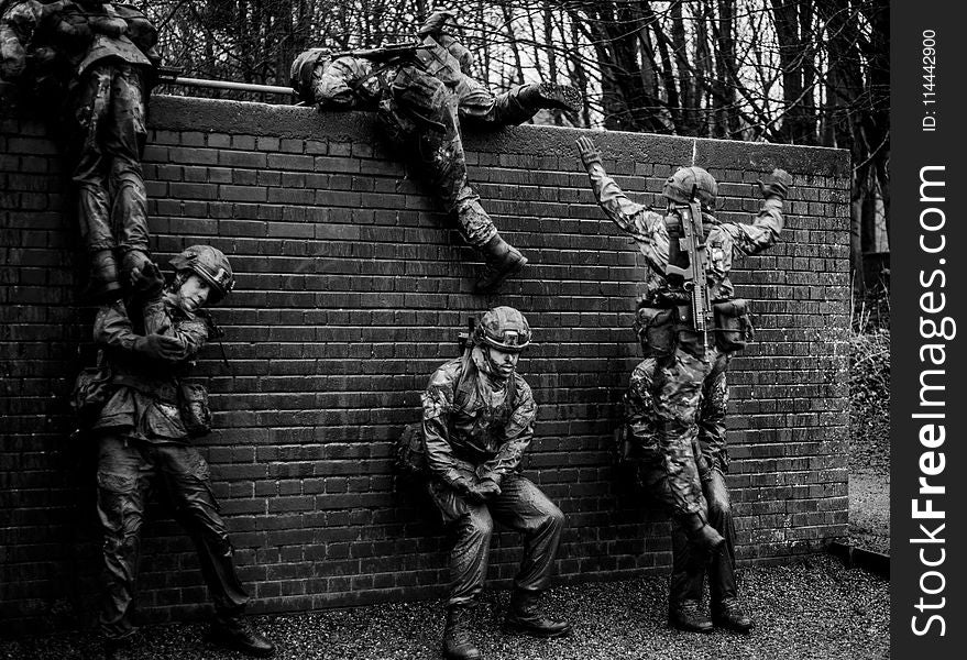 Grayscale Photography Of Soldiers Climbing Over Fence