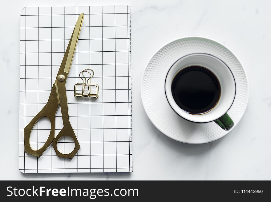 Cup of Coffee Beside Book and Scissors