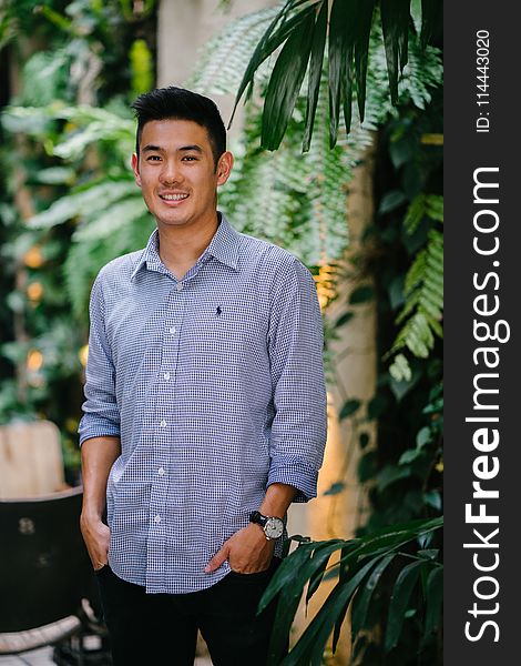 Man Wearing Blue Dress Shirt Standing Beside Green Plant