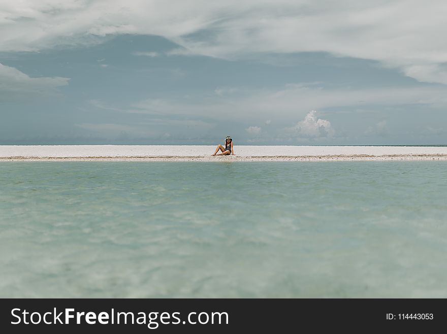 Person Sitting On White Sand