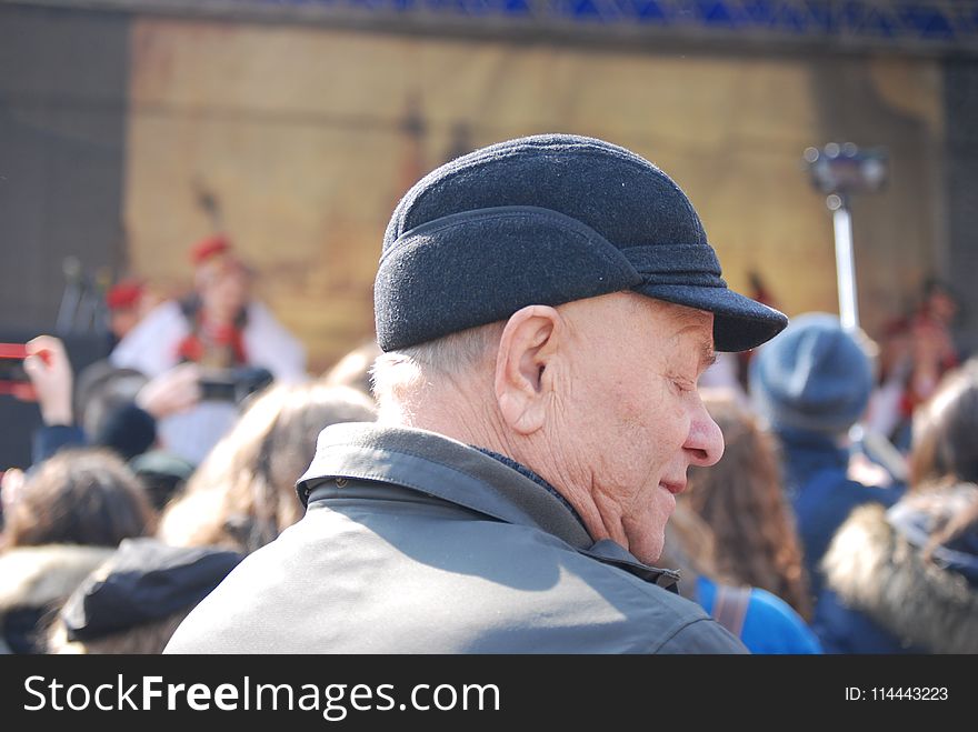 Man Wearing Cap And Grey Coat Surrounded With People
