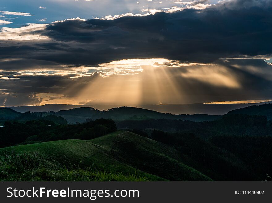 Beans of light shone through the clouds as the sun set of Papamoa hills near Tauranga on New Zealand`s North island. Beans of light shone through the clouds as the sun set of Papamoa hills near Tauranga on New Zealand`s North island