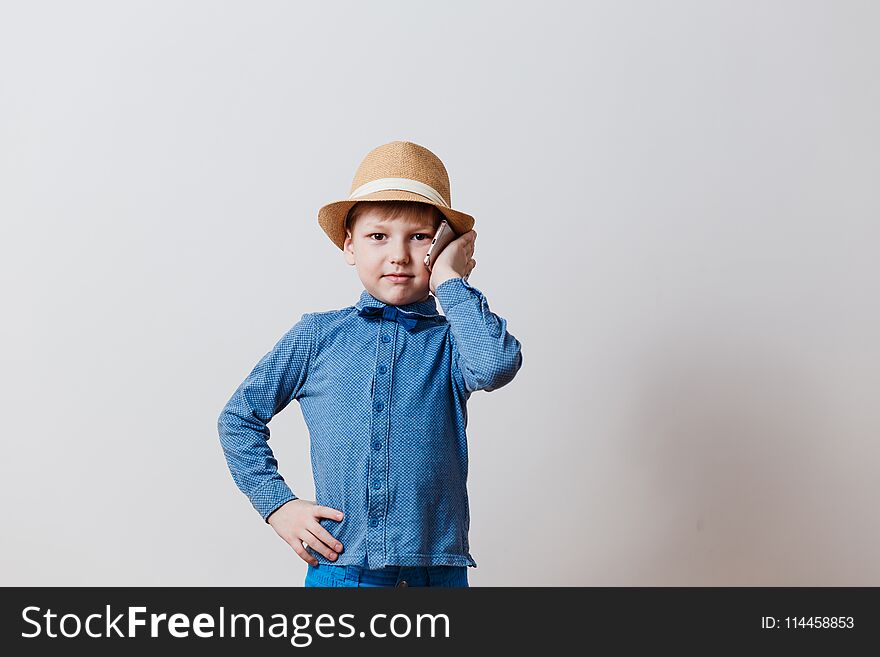 Little Boy In Blue Shirt In Hat Talking On Phone On White Background