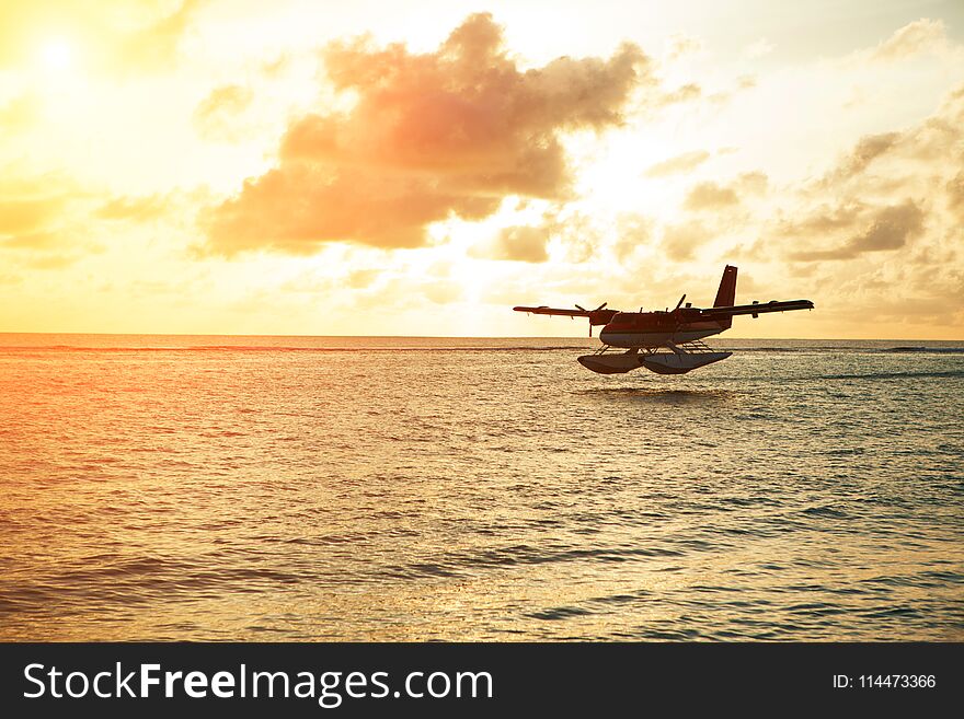 Summer sunrise with seaplane. Landing seaplane on the seashore. Calm scenery on morning sea.