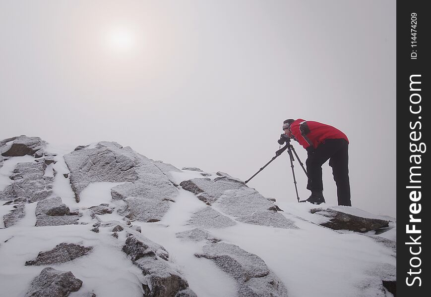 Tall hiker in black on peak of the world . Heavy orange mist bellow in valley.