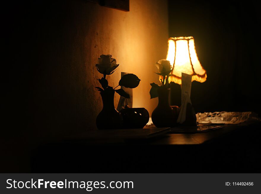 Evening lamp with roses and warm light in vintage room of cafe