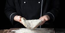 Female Chef Holding Yeast Dough In Her Hands On Black Background Stock Photography
