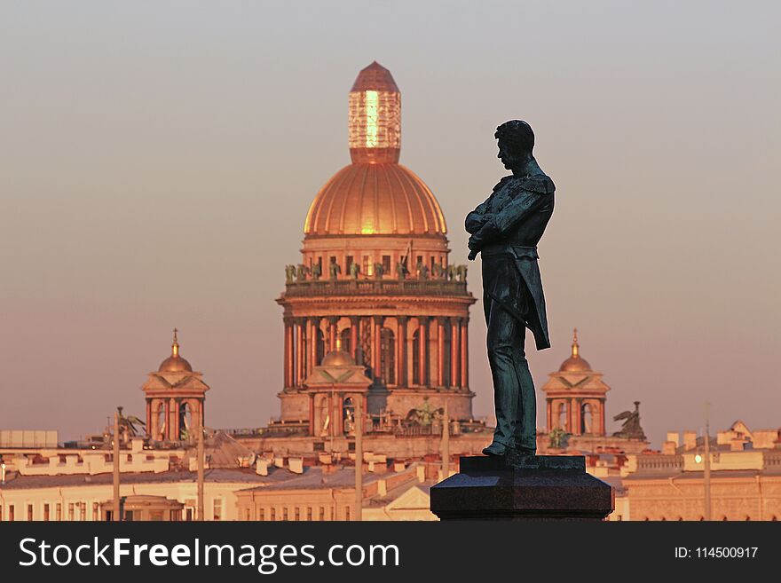 Russia, St. Petersburg, a monument to Admiral Kruzenshtern on the background of St. Isaac`s Cathedral at sunset
