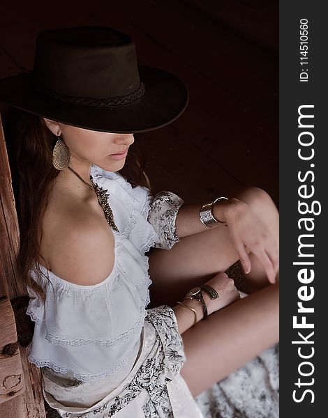 Photo of Woman in White Off-shoulder Top and Brown Cowboy Hat Sitting