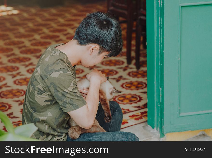 Photo Of Boy Wearing Camouflage Shirt Holding A Cat