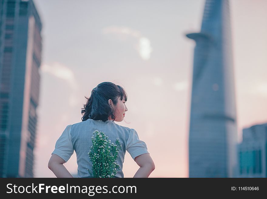 photo of Woman in Gray Top Holding Flowers on Her Back