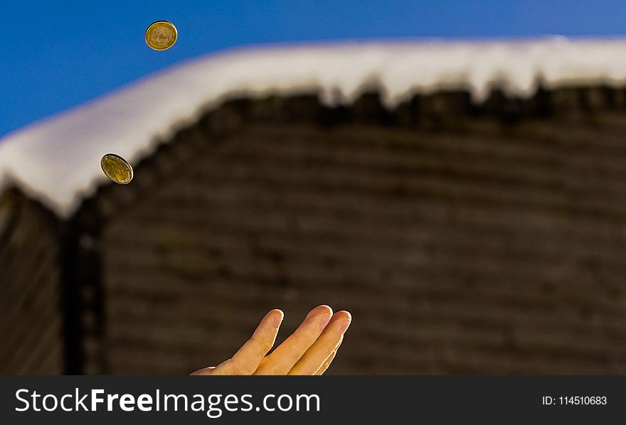 Shallow Focus Photography of Person Catching Two Gold-colored Coins