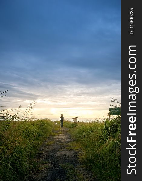 Person Wearing Black Shirt Walking Near Grass Field