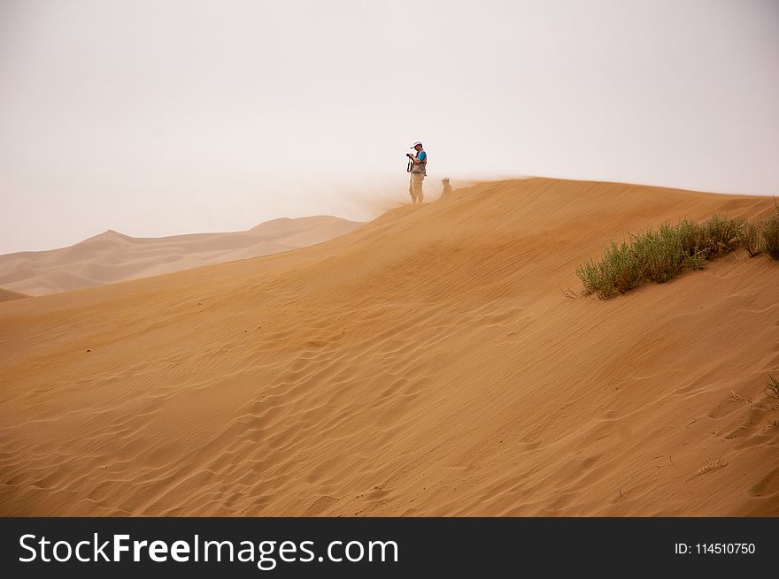 Man Standing on Brown Sand Under Gray Sky