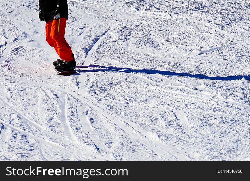 Photo of Person Wearing Black Top and Orange Pants Riding Snowboard