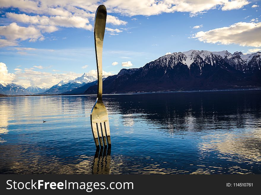 Gray Stainless Steel Fork on Water With Overlooking Mountain at Daytime