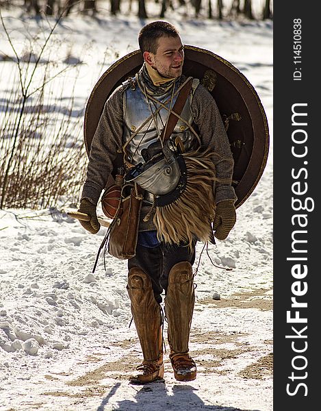 Man Wearing Armor and Walking in Snowy Field