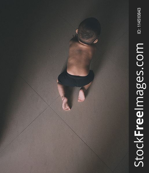 Toddler In Black Shorts Crawling On Grey Floor Tiles