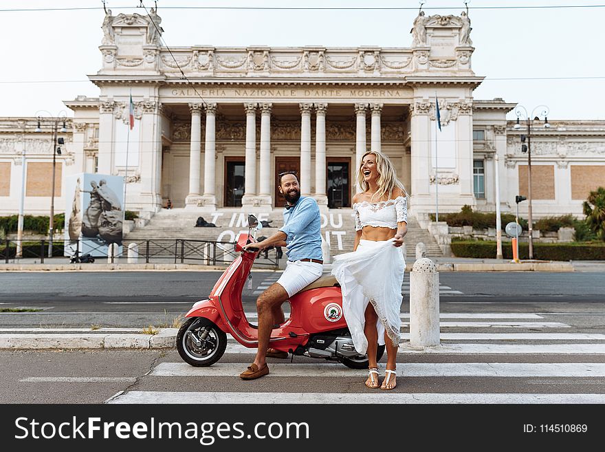 Man Riding on the Motorcycle Beside Woman Standing on the Road