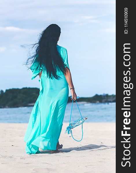 Woman in Teal Dress Standing on Beach