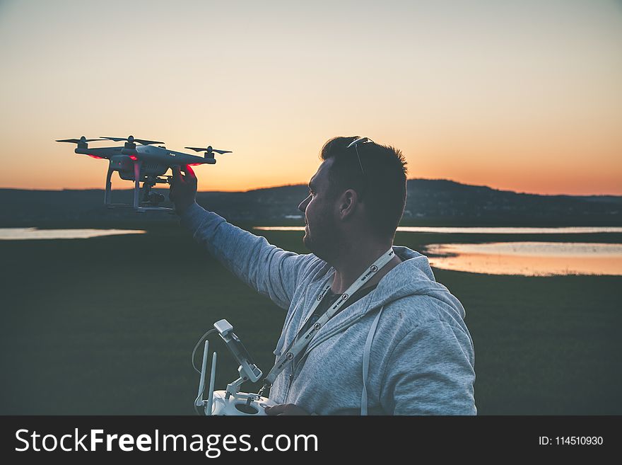 Man in Gray Jacket Holding Black Drone
