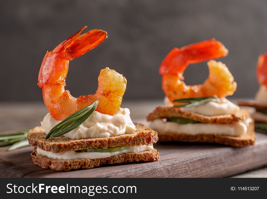 Delicious small sandwiches with shrimps on wooden board