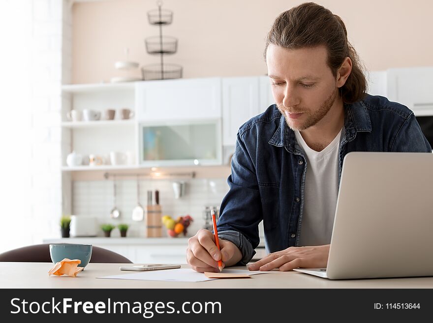 Young Man Working With Laptop At Desk In Home