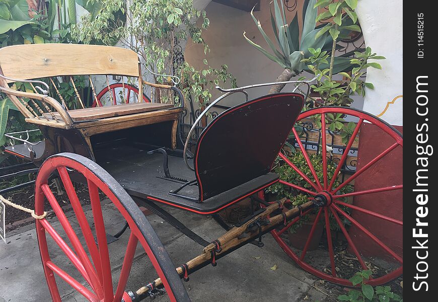 This vintage wooden and iron buggy has painted red wheels. This vintage wooden and iron buggy has painted red wheels.