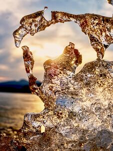 Shiny Cold Ice, Bright Icicles On Frozen Lake Shore. Warm Sun Rays Of Sunset. Reflection Royalty Free Stock Photography Shiny Cold Ice, Bright Icicles On Frozen Lake Shore. Warm Sun Rays Of Sunset. Reflection Royalty Free Stock Photography