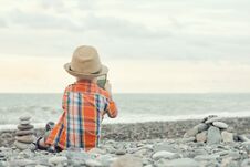 Little Boy Takes Pictures On The Smart Phone. Sits On A Pebble B Royalty Free Stock Images