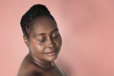 African Woman Standing Against A Pink Background With Eyes Closed Stock Image