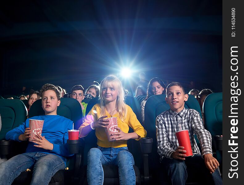 Youth watching film and eating snacks in movie theatre.