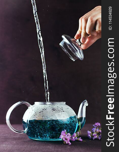 Blue Butterfly Pea tea poured in a glass teapot on a table, Clitoria Ternatea tea, selective focus, dark background