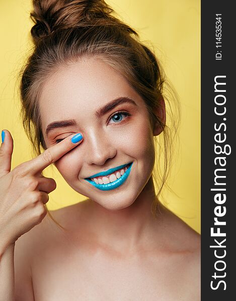 Beauty art portrait of white young smiling girl in punchy pastel tones. blue caramel makeup on yellow background. Vertical photo. Beauty art portrait of white young smiling girl in punchy pastel tones. blue caramel makeup on yellow background. Vertical photo