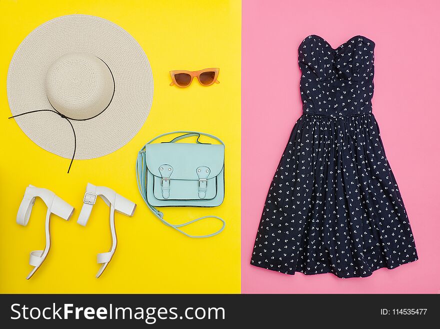 Fashionable concept. Female summer wardrobe. Straw hat, sundress, handbag and shoes. Yellow and pink background, top view