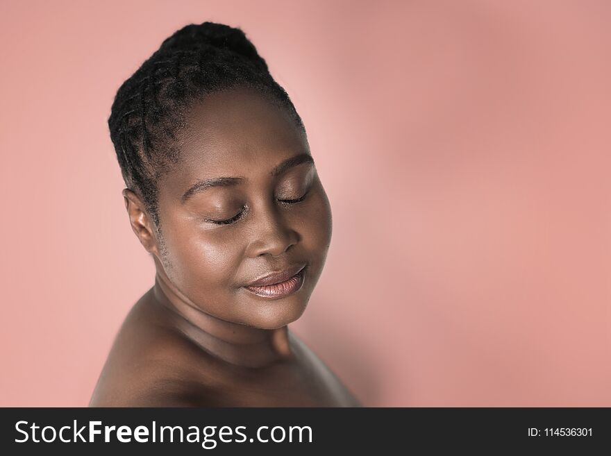 Attractive young plus size African woman with beautiful skin standing with her eyes closed against a blooming dahlia colored background. Attractive young plus size African woman with beautiful skin standing with her eyes closed against a blooming dahlia colored background