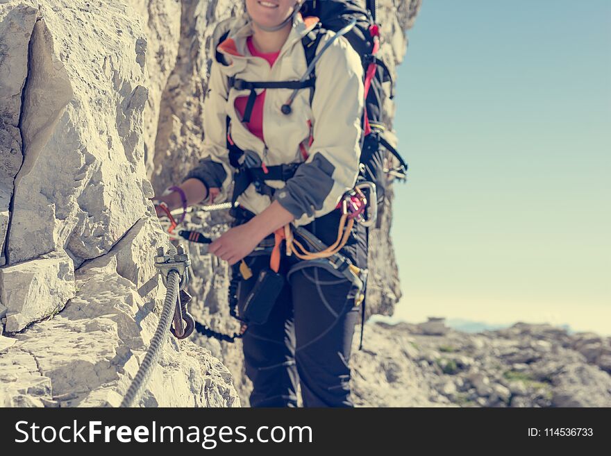 Closeup of female climber attaching via ferrata set. Climbing Sentiero delle Bocchette Alte.