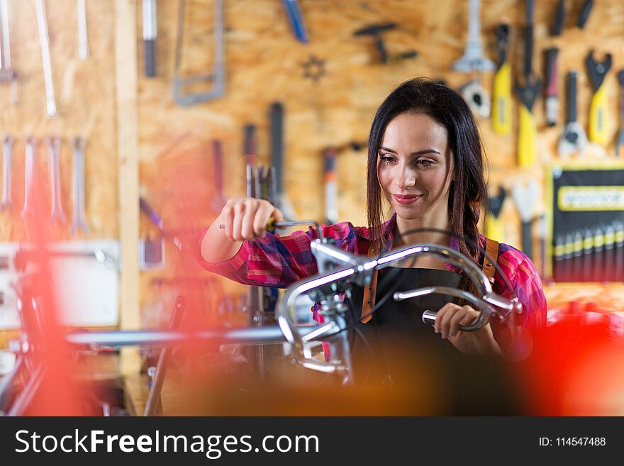 Young woman working in a bicycle repair shop