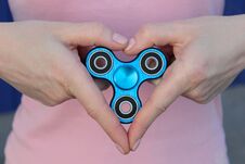 Girl Is Playing Blue Metal Spinner In Hands On The Street, Woman Playing With A Popular Fidget Spinner Toy, Girl Love Anxiety Reli Royalty Free Stock Images