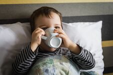 Unhealthy Little Boy Drinking Cup Of Medicament Lying On Bed Stock Photos
