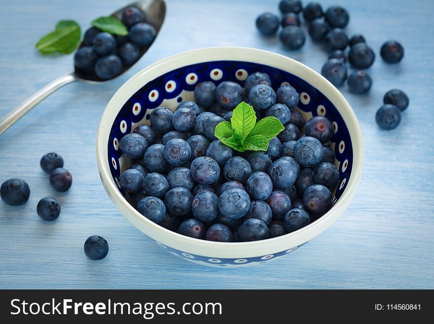 Fresh blueberries in a bowl on blue background