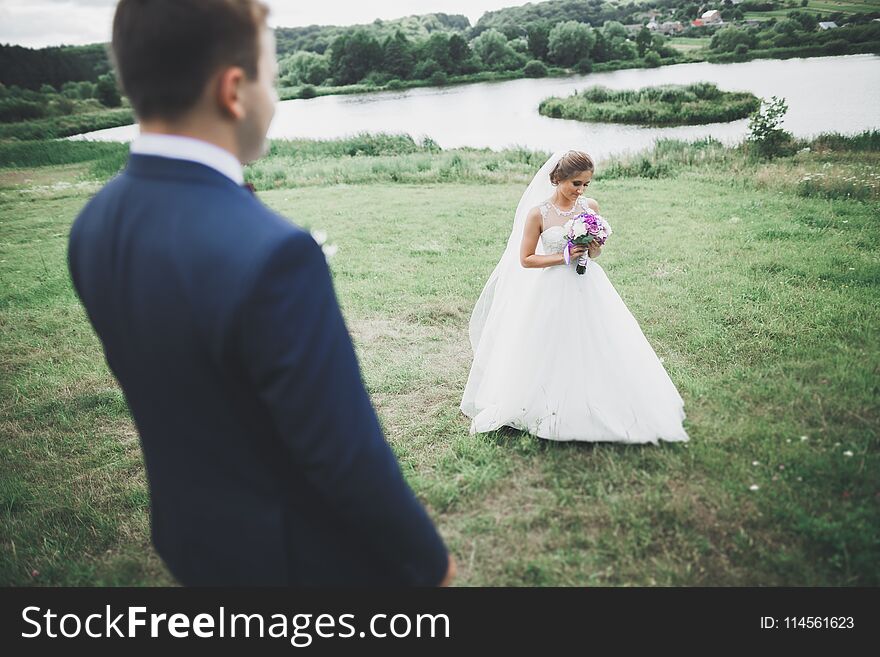 Newly married couple running and jumping in park while holding hands.