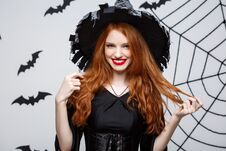 Halloween Witch Concept - Happy Halloween Witch Holding Posing Over Dark Grey Studio Background With Bat And Spider Web. Stock Photo
