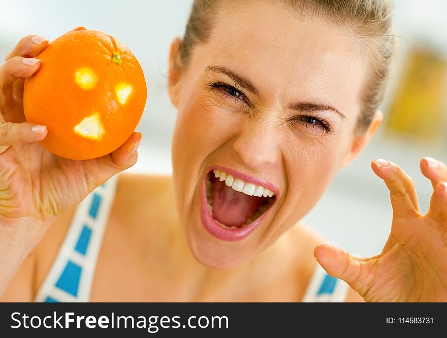 Young woman scaring with orange with hallowing face