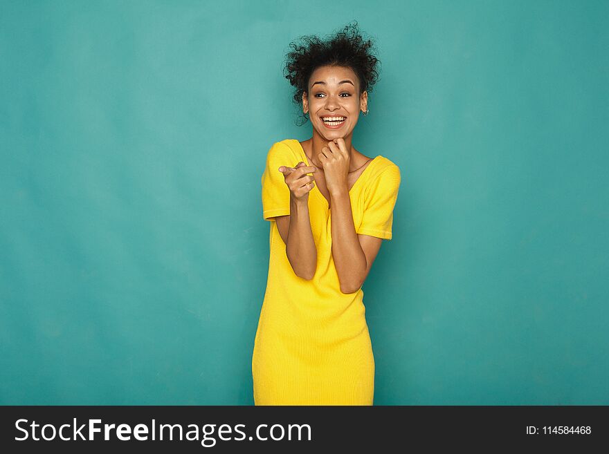 Smiling african-american woman pointing to camera, at blue studio background, copy space. Smiling african-american woman pointing to camera, at blue studio background, copy space